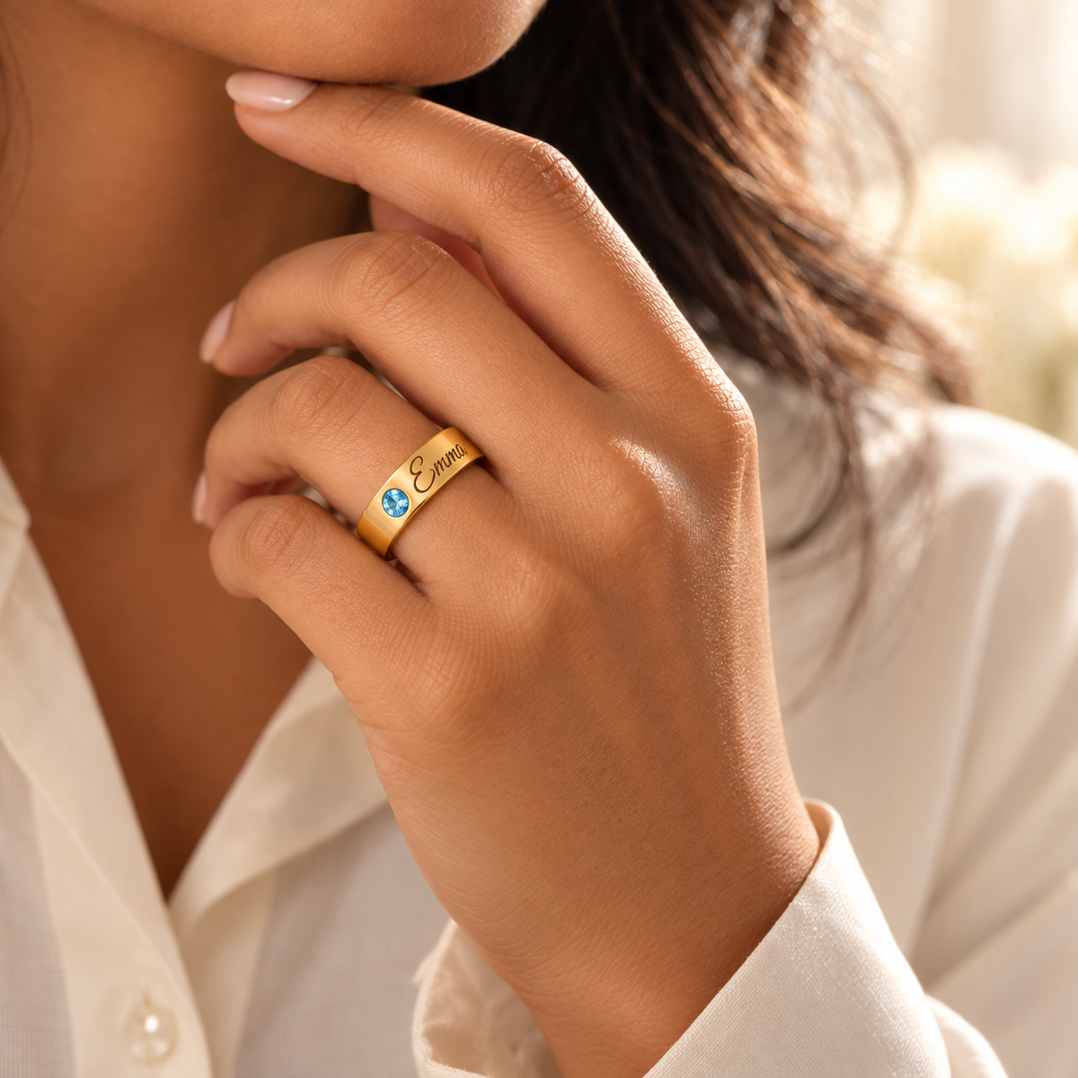Custom Wide Band Name Ring with Birthstone professional lifestyle photo - gold Blue Topaz ring with Emma engraving worn near a models chin Anthology Jewelry