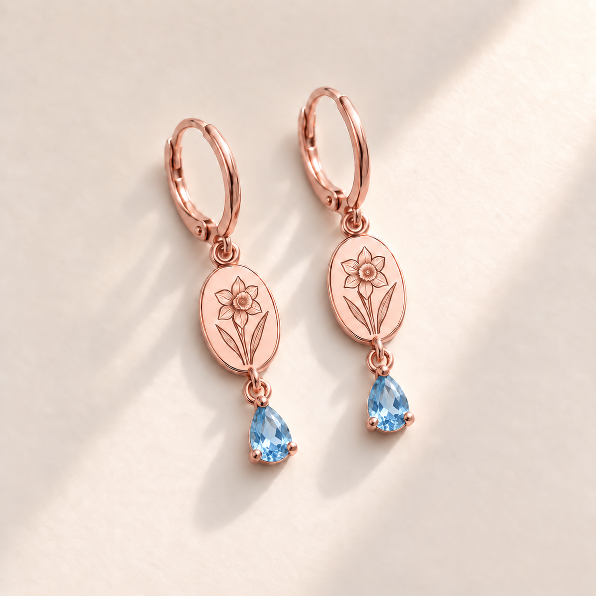Custom Birth Flower & Birthstone Drop Earrings December rose gold hero photo - narcissus engraving and faceted blue topaz pear stones Anthology Jewelry