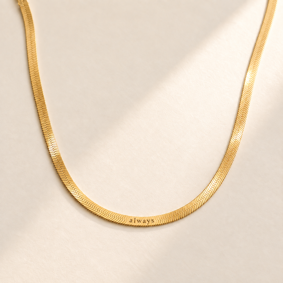 Custom Engraved Herringbone Necklace hero photo - gold herringbone chain on pale ivory Anthology Jewelry