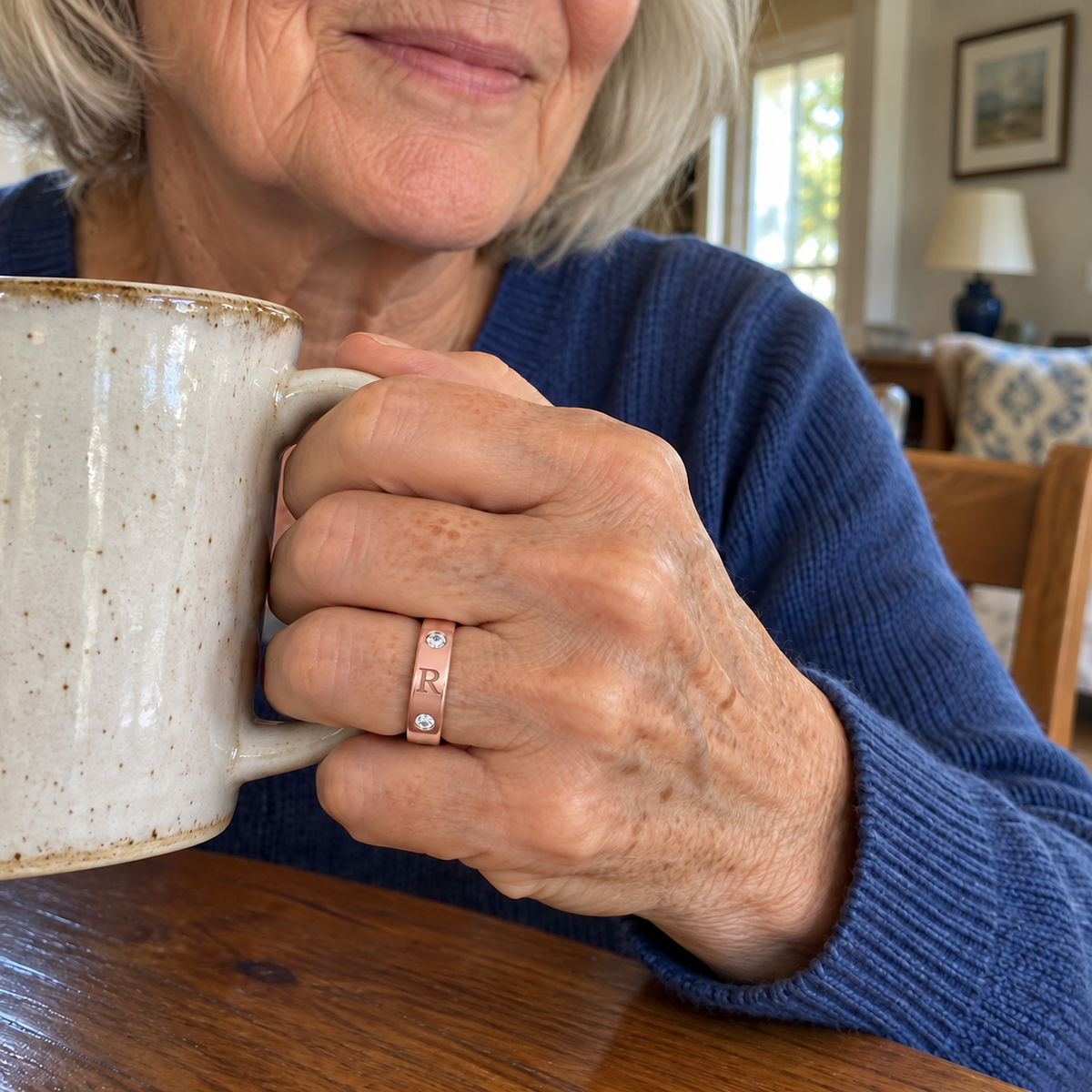 Custom Flush Stone Initial Band in rose gold with R personalization, casual phone-style worn view with a mug at home - Anthology Jewelry