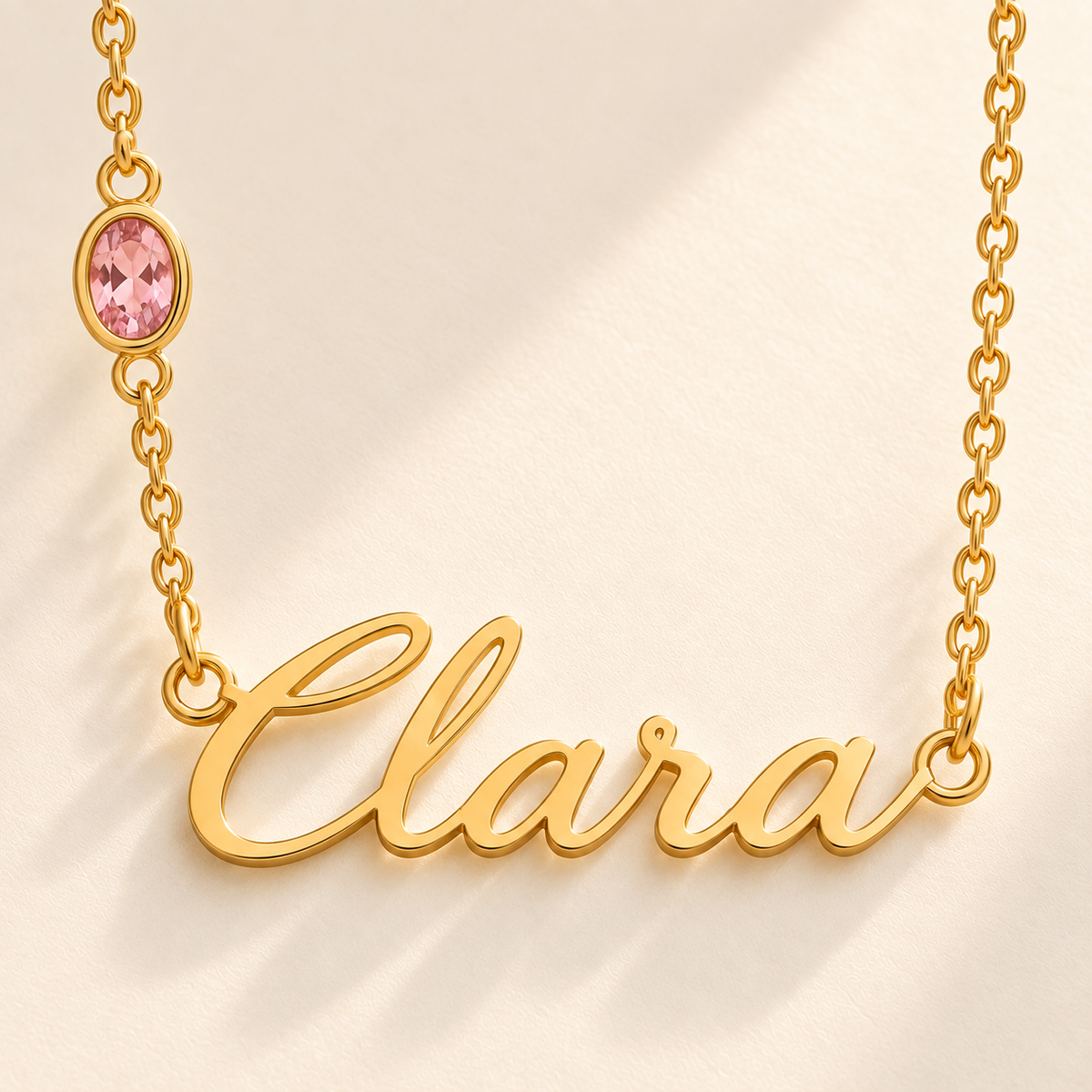 Custom Offset Birthstone Script Name Necklace macro detail photo - complete gold Clara script nameplate and October pink oval gemstone in the left chain Anthology Jewelry