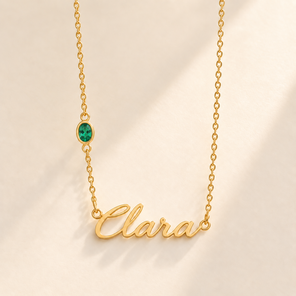 Gold script Clara necklace with may birthstone-color stone on left chain