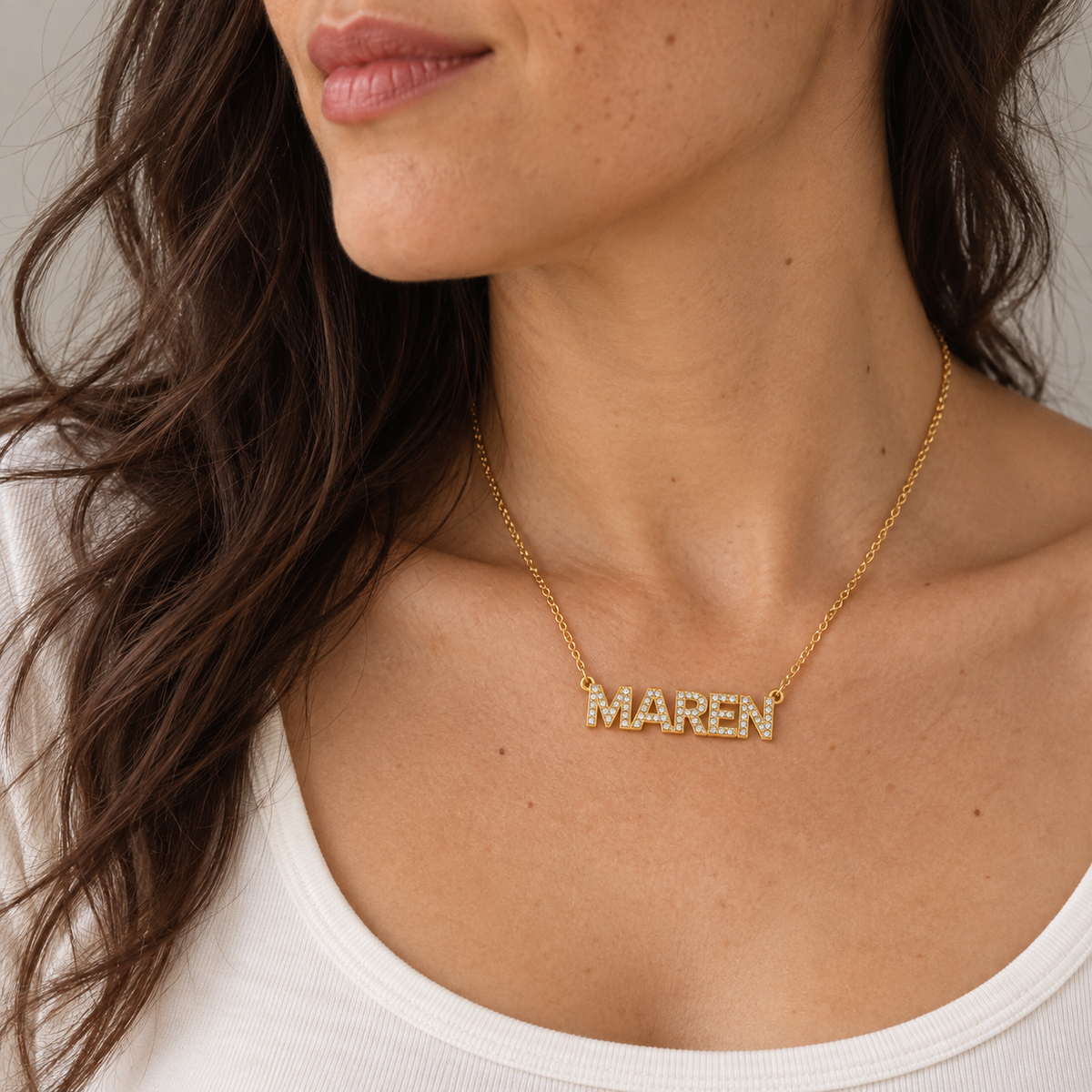 Woman wearing a gold MAREN pavé name necklace at the collarbone