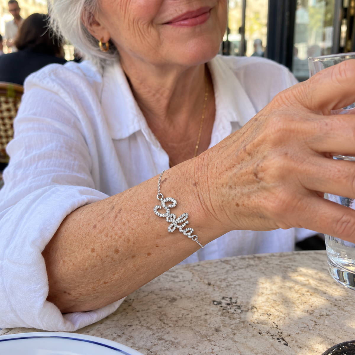 Custom Pavé Script Name Bracelet in silver with Sofia personalization, worn at a cafe; illustrative phone-style marketing image - Anthology Jewelry