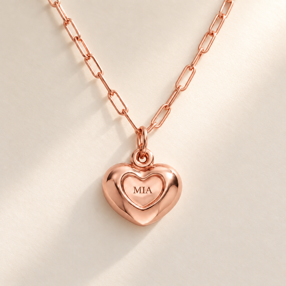 Custom Puffy Heart Necklace hero photo - rose gold heart with MIA engraving and soft consistent diagonal light Anthology Jewelry