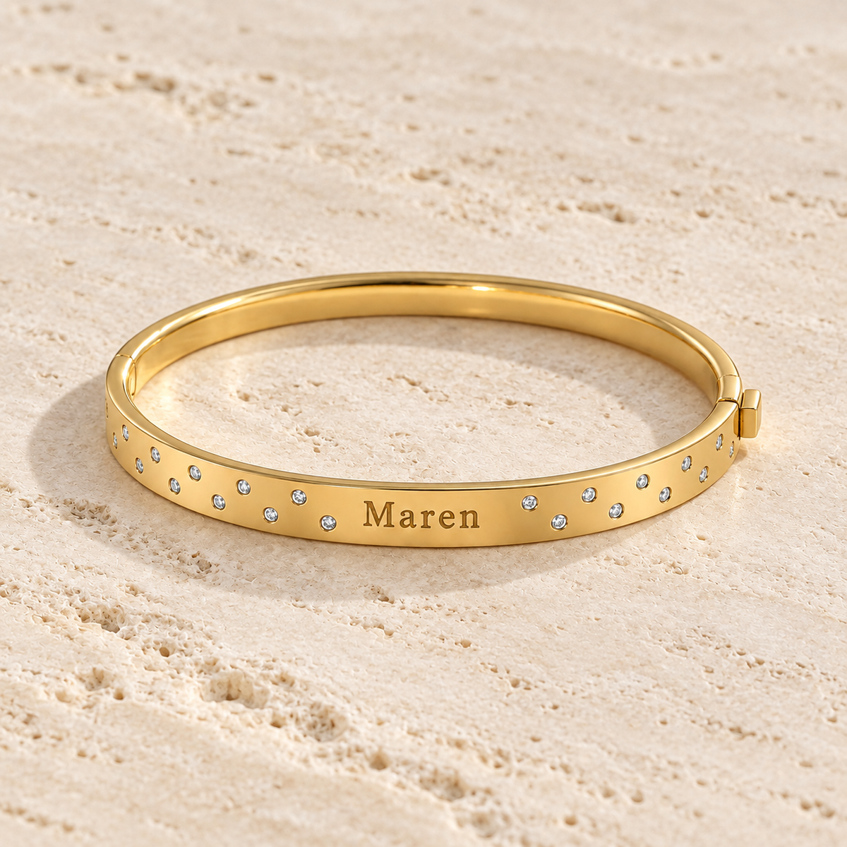 Gold hinged name bangle showing its engraved front and scattered stones