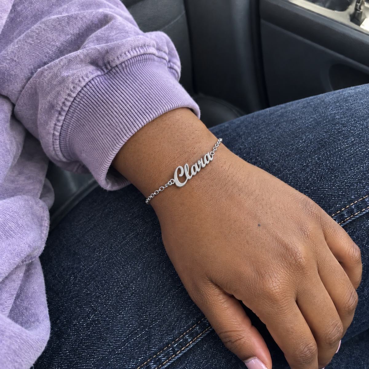 Custom Script Name Bracelet in silver with Clara personalization, worn on a car passenger wrist; illustrative phone-style marketing image - Anthology Jewelry