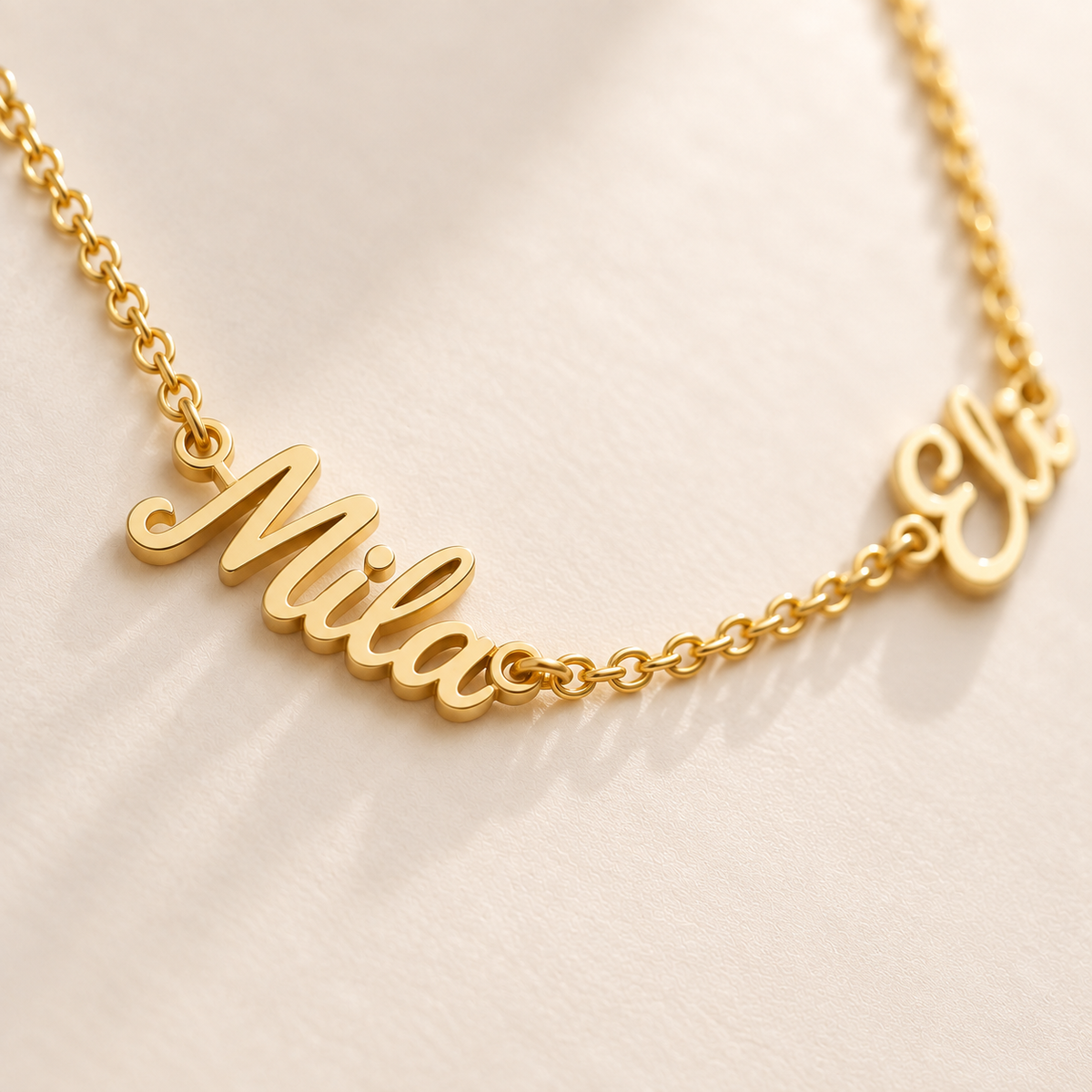 Custom Spaced Names Necklace detail photo - macro of two separate connected script names on a fine rolo chain Anthology Jewelry