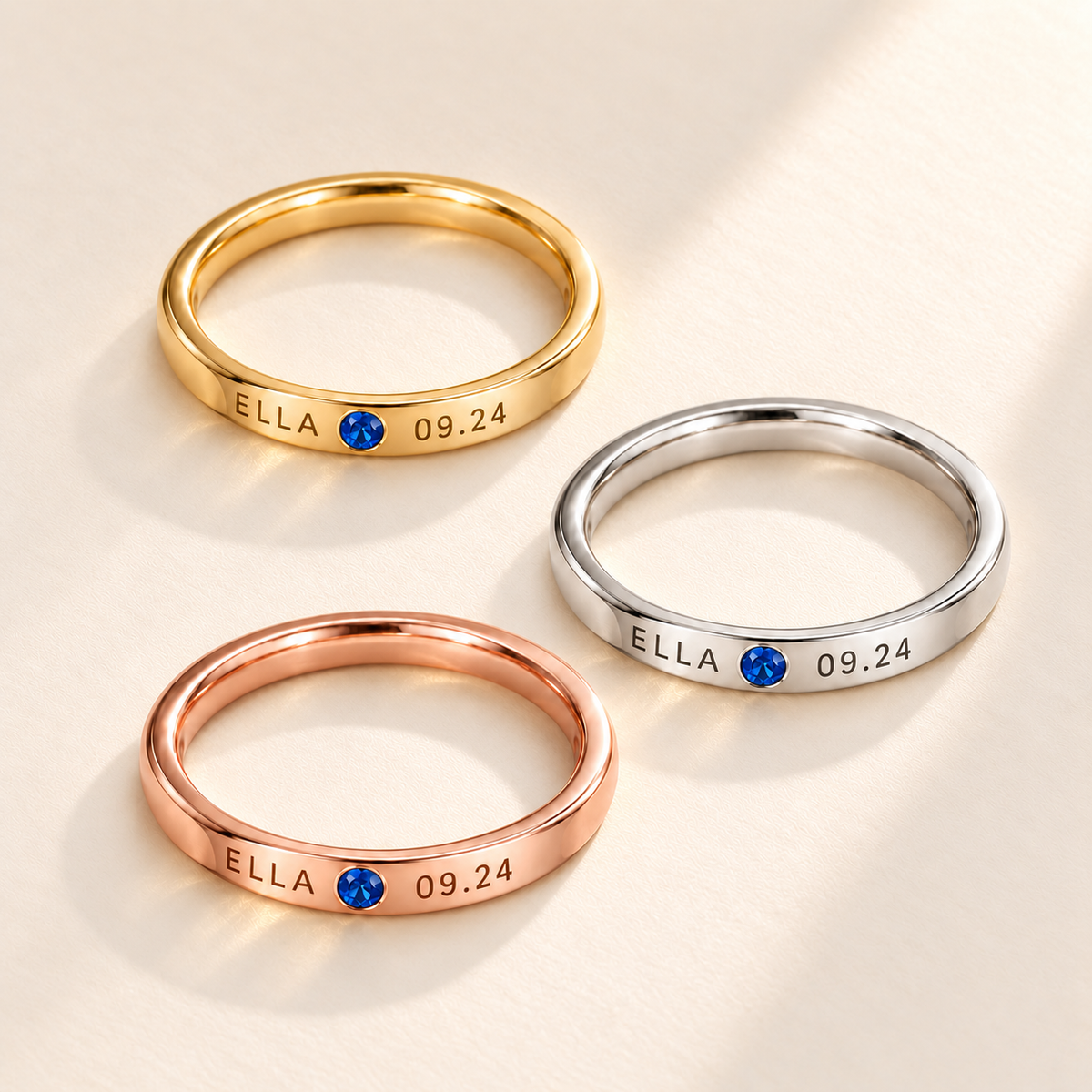 Custom Date & Name Birthstone Stacking Ring glamour photo - gold, silver and rose gold rings on a cream surface Anthology Jewelry