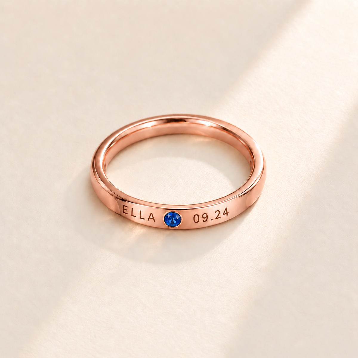Custom Date & Name Birthstone Stacking Ring Rose Gold hero photo - ELLA and 09.24 engraving beside a blue birthstone Anthology Jewelry