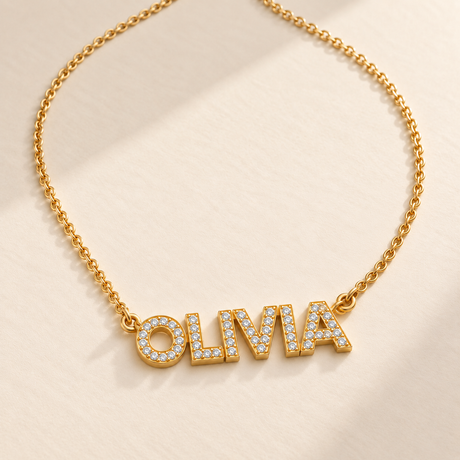 Custom Pavé Name Necklace hero photo - gold OLIVIA pavé name necklace on cream surface Anthology Jewelry