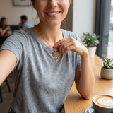 Custom Birth Flower & Birthstone Necklace UGC photo - customer wearing gold carnation birth flower and garnet necklace at a cafe Anthology Jewelry