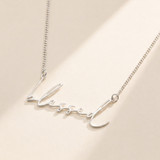 "Blessed" Necklace hero photo - sterling silver script cutout pendant on cream background Anthology Jewelry