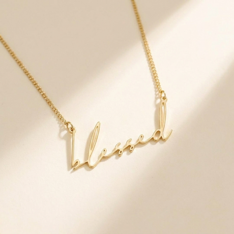 "Blessed" Necklace hero photo - gold script cutout pendant on cream background Anthology Jewelry
