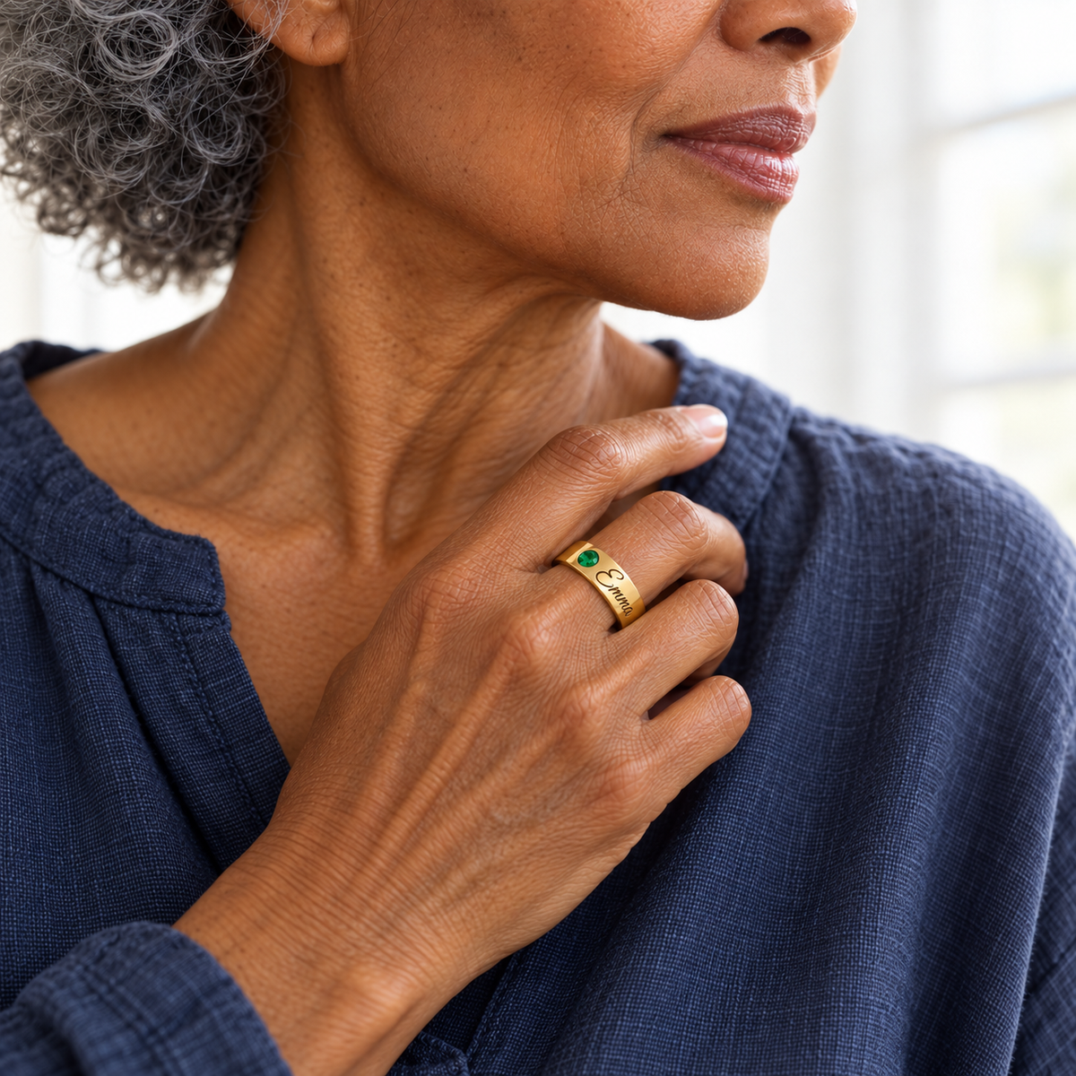 Custom Wide Band Name Ring with Birthstone professional lifestyle photo - gold emerald ring with Emma engraving worn by a mature model Anthology Jewelry