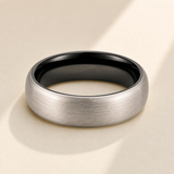 Classic Brushed Tungsten Wedding Band hero photo - two-toned tungsten ring with black interior on display Anthology Jewelry