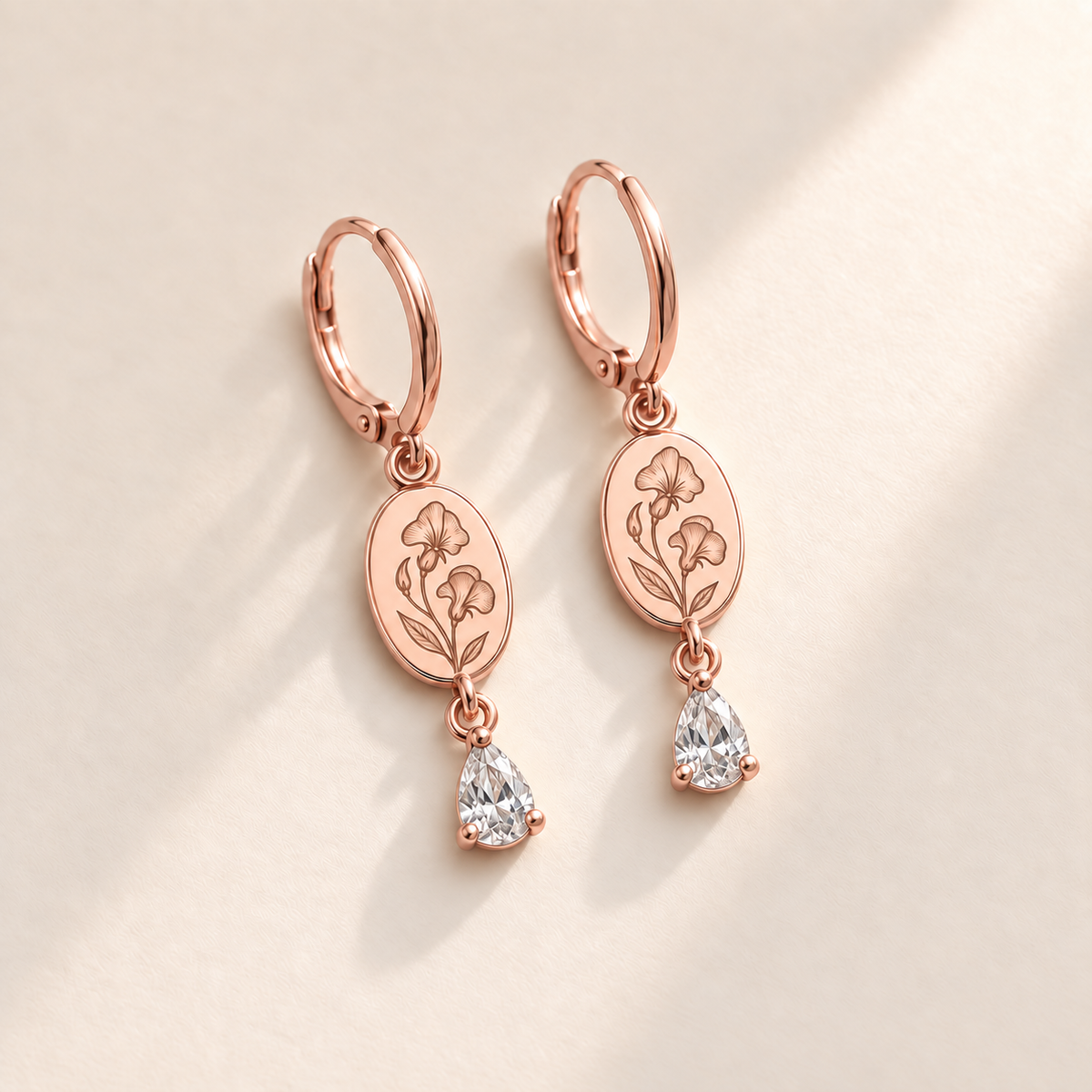 Custom Birth Flower & Birthstone Drop Earrings april rose gold hero photo - engraved two sweet-pea flowers, small bud and two leaves with clear colorless pear stones Anthology Jewelry