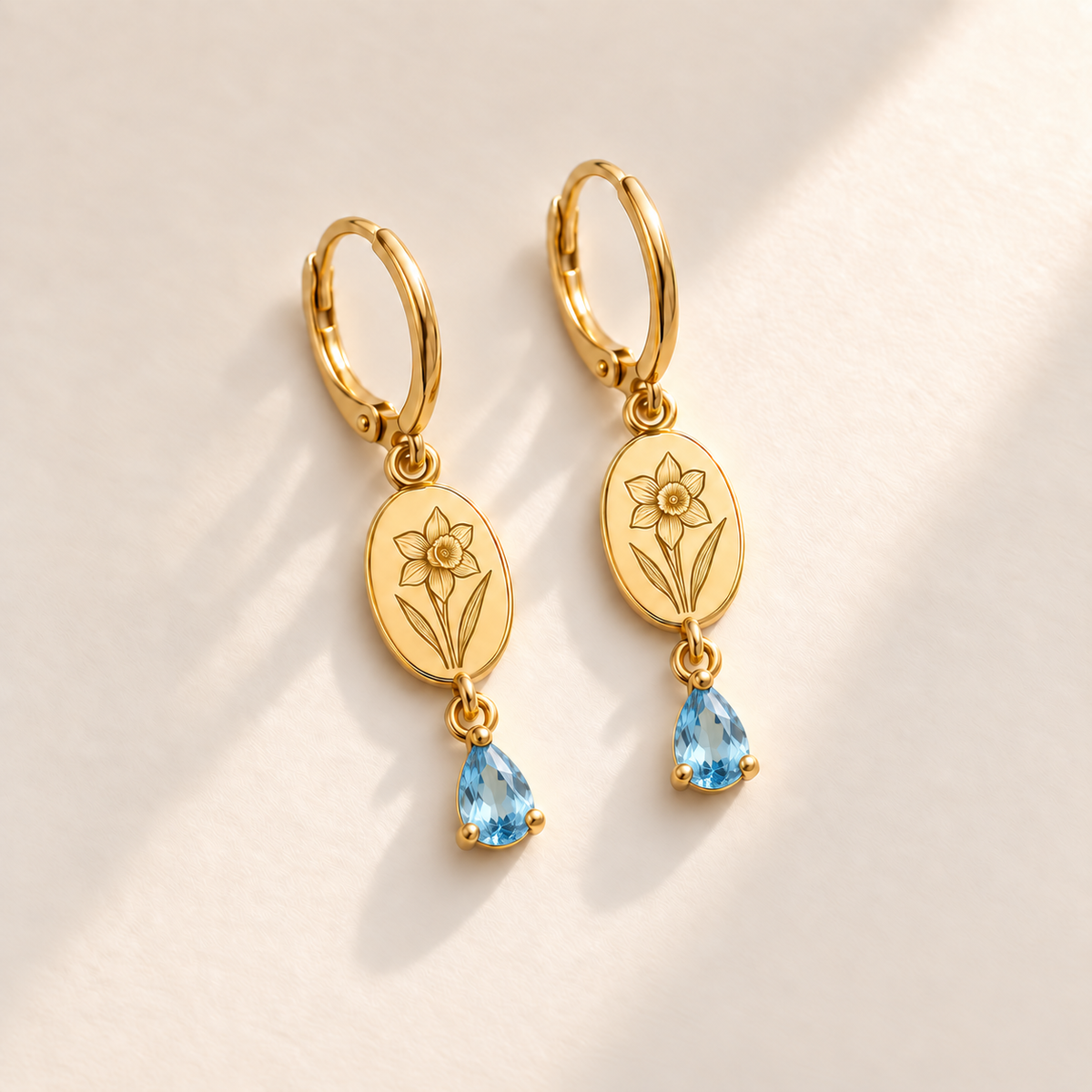 Custom Birth Flower & Birthstone Drop Earrings December gold hero photo - narcissus engraving and faceted blue topaz pear stones Anthology Jewelry