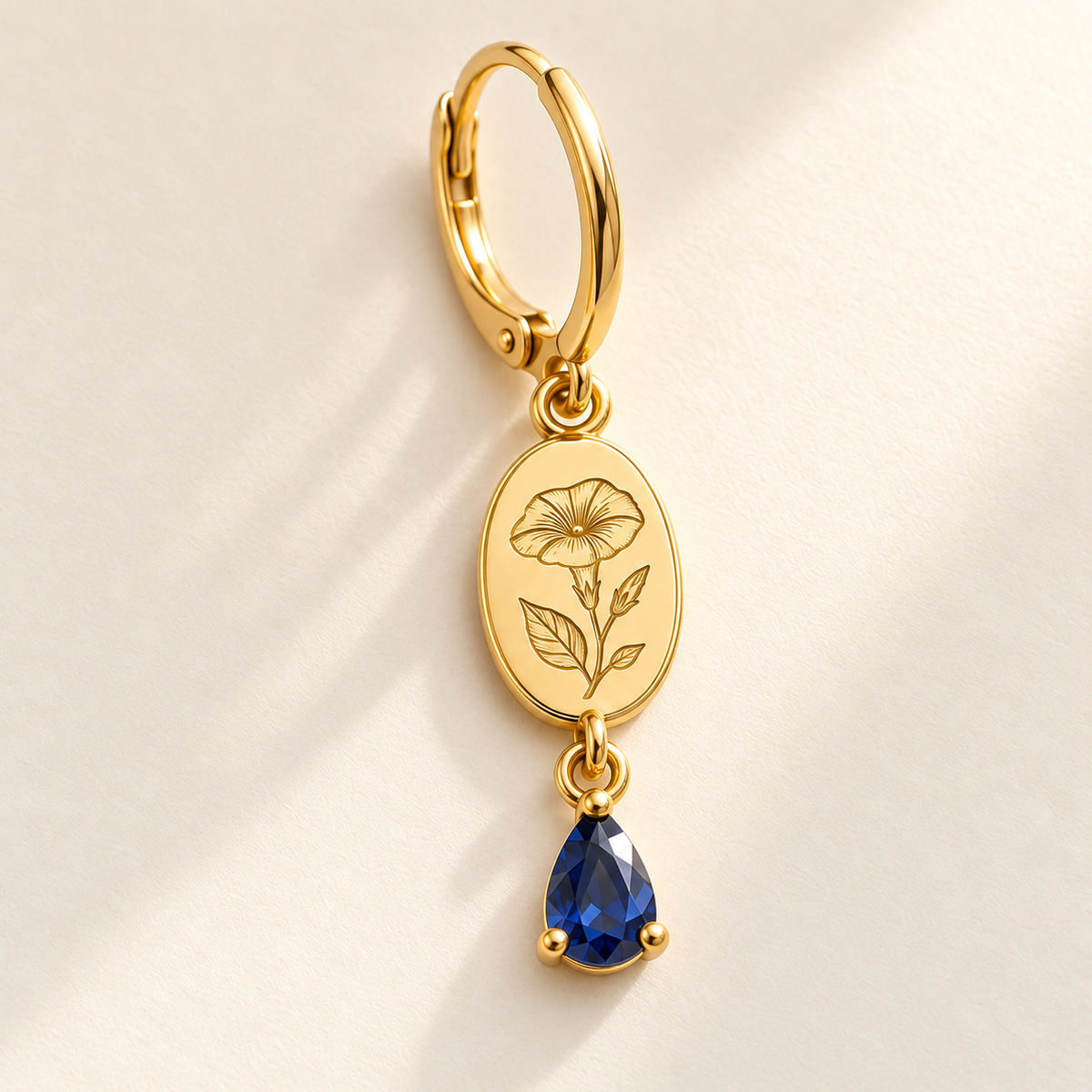 Custom Birth Flower & Birthstone Drop Earrings macro detail photo - complete gold morning glory engraved oval medallion, hinged hoop and September blue pear gemstone Anthology Jewelry