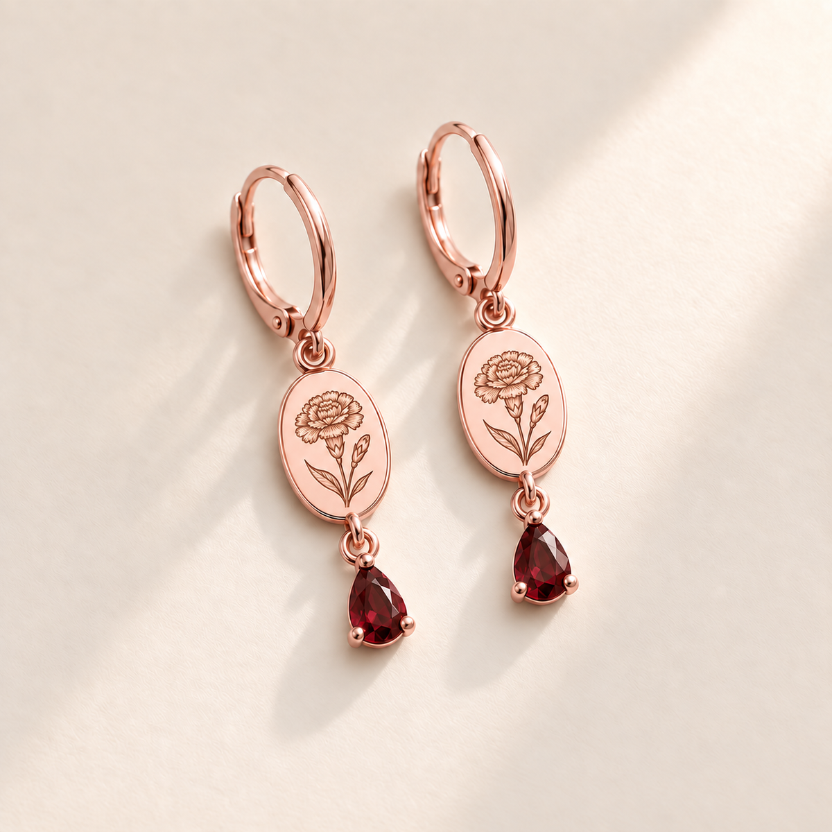Custom Birth Flower & Birthstone Drop Earrings january rose gold hero photo - engraved carnation flower with ruffled petals, right bud, narrow leaves with dark garnet red pear stones Anthology Jewelry