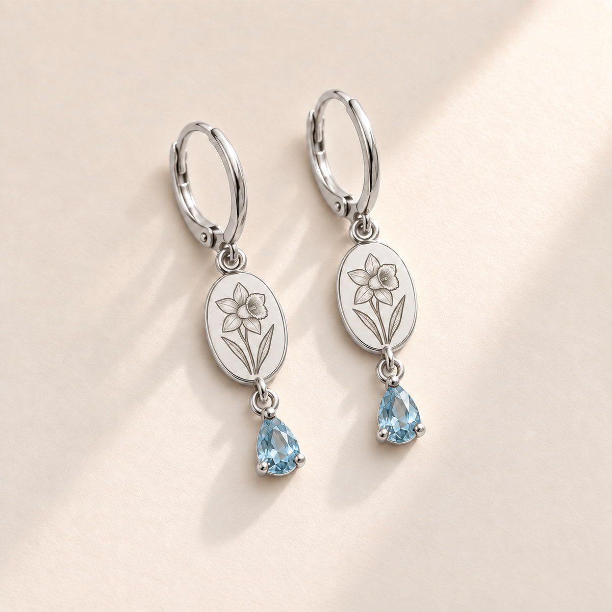 Custom Birth Flower & Birthstone Drop Earrings march silver hero photo - engraved daffodil flower with trumpet pointing right and two long leaves with pale aquamarine blue pear stones Anthology Jewelry
