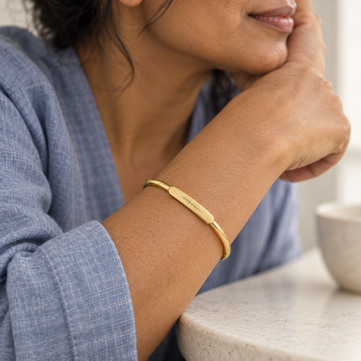 Custom Classic Hinge Bangle professional close photo - gold soundwave bangle worn with blue linen Anthology Jewelry
