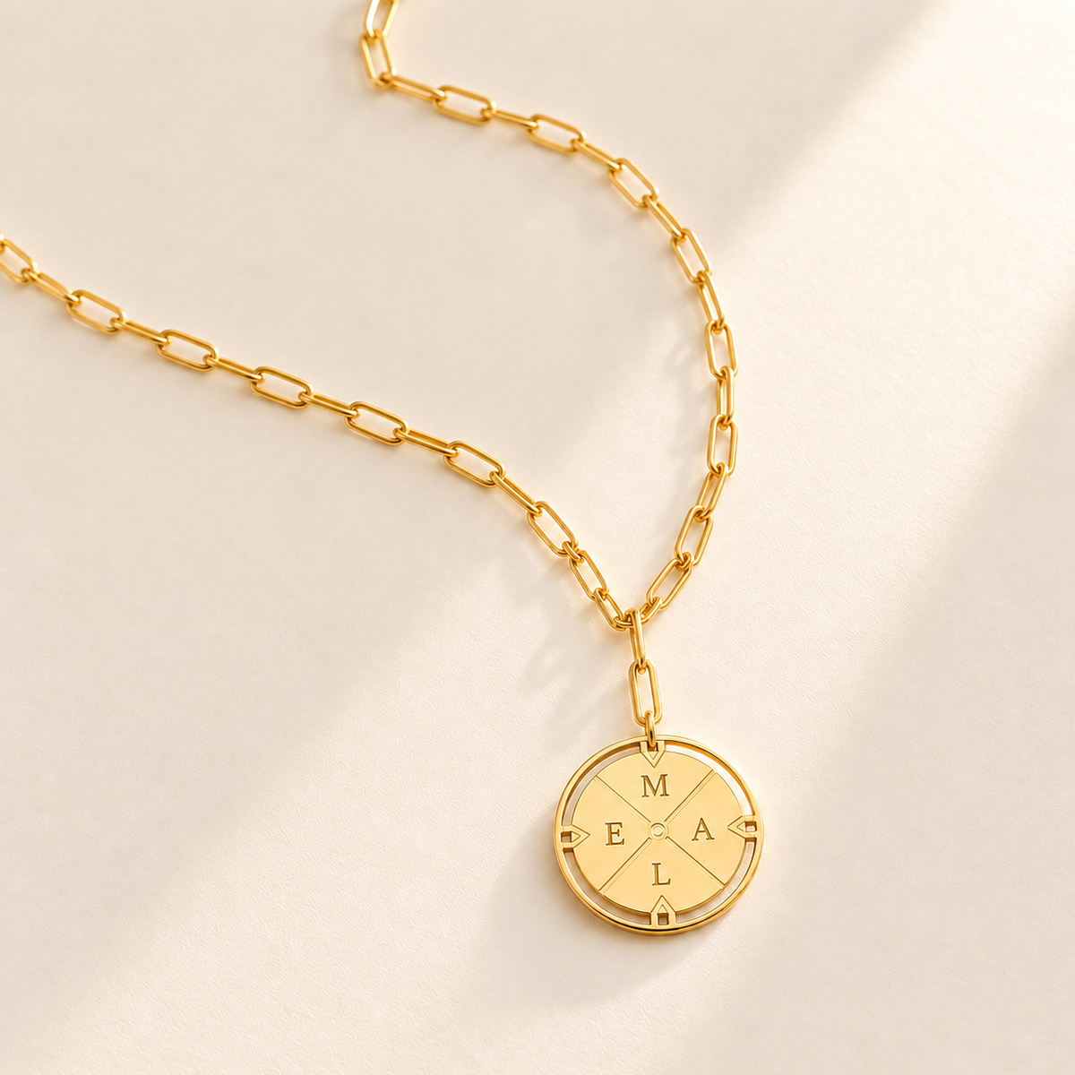 Custom Compass Initial Necklace hero photo - gold compass initials pendant and relaxed paperclip chain on pale ivory Anthology Jewelry