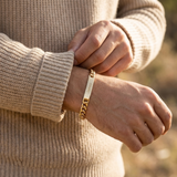 Custom Curb Chain ID Bracelet lifestyle photo - man adjusting sweater sleeve wearing engraved gold curb chain bracelet Anthology Jewelry