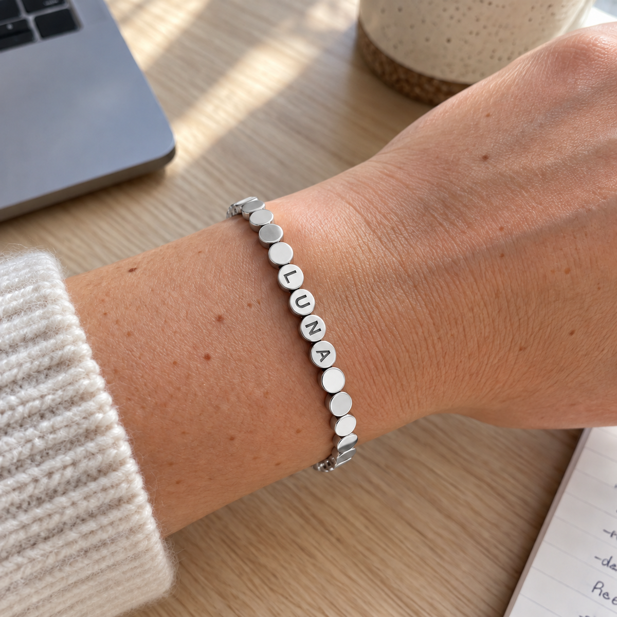 Custom Engraved Dot Bracelet in silver with LUNA personalization, worn at a desk; illustrative phone-style marketing image - Anthology Jewelry