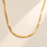 Custom Engraved Herringbone Necklace hero photo - gold herringbone chain on pale ivory Anthology Jewelry
