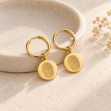 Custom Fingerprint Huggie Hoop Earrings glamour photo - gold earrings styled on ivory ceramic dish Anthology Jewelry