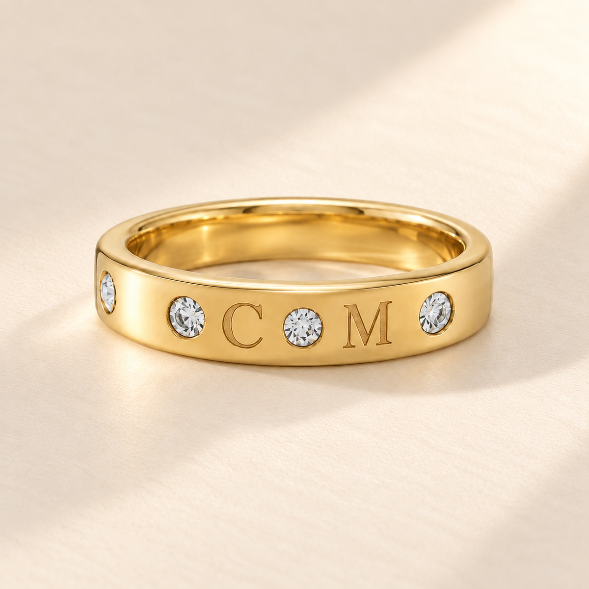 Gold initial band with C M engraving, four stones and uniform width