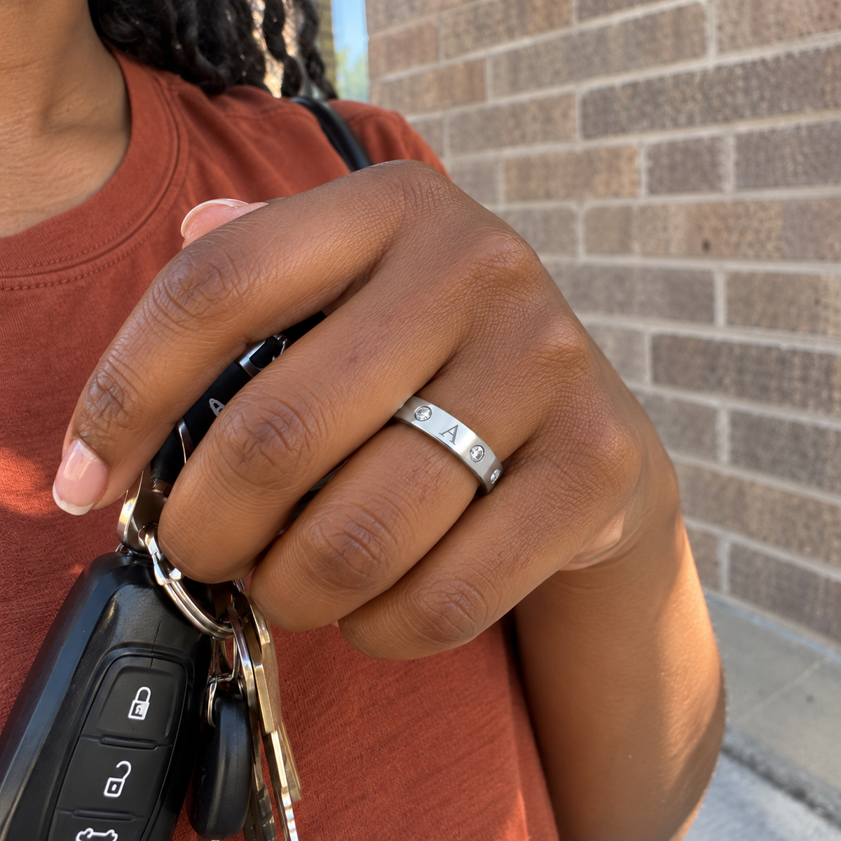 Custom Flush Stone Initial Band in silver with A personalization, casual phone-style worn view while holding keys - Anthology Jewelry