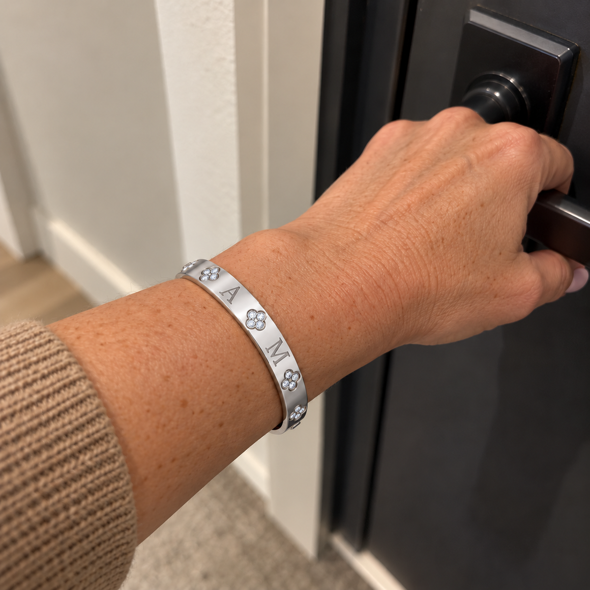 Custom Four-Stone Initial Bangle in silver with A / M personalization, worn at a door; illustrative phone-style marketing image - Anthology Jewelry