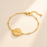 Custom Handwriting Bracelet Disc Pendant hero photo - gold disc bracelet engraved with handwriting on cream background Anthology Jewelry
