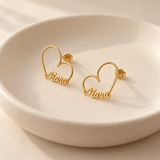 Custom Heart-Frame Name Stud Earrings gold pair in an ivory ceramic dish - Anthology Jewelry