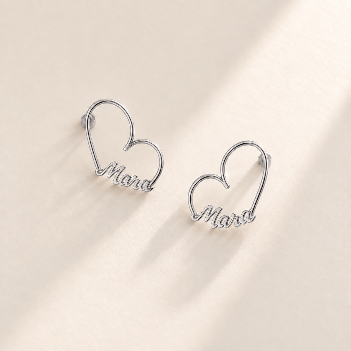 Custom Heart-Frame Name Stud Earrings silver variant hero on pale ivory background - Anthology Jewelry
