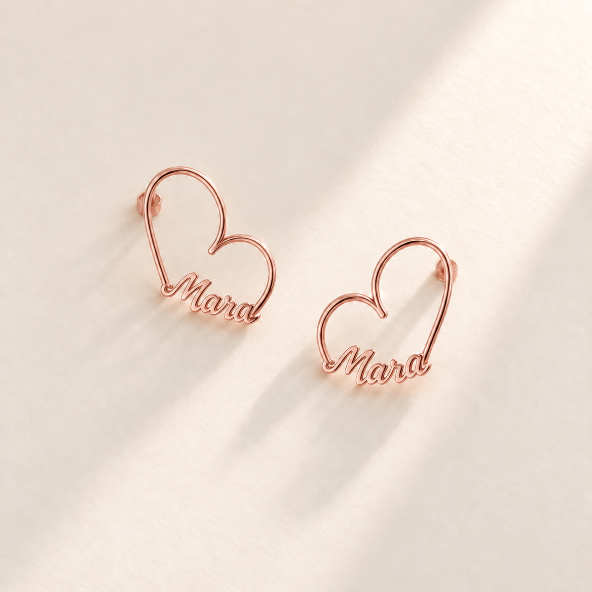 Custom Heart-Frame Name Stud Earrings rose gold variant hero on pale ivory background - Anthology Jewelry