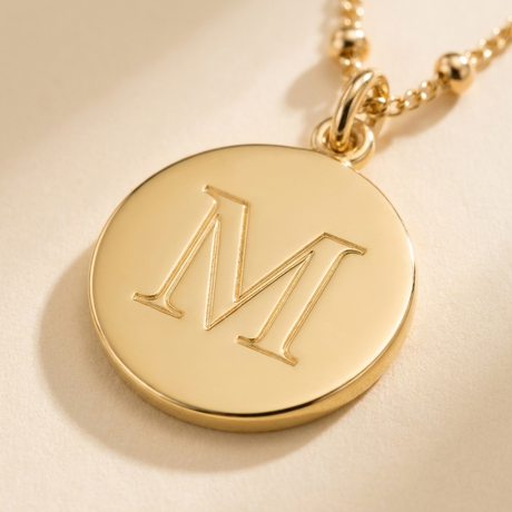 Custom Initials Necklace detail photo - close-up of engraved serif initial on gold disc Anthology Jewelry