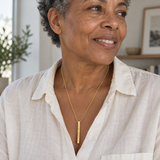 Gold medium column necklace worn in a close professional portrait