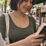 Gold medium column necklace worn at a neighborhood book stall
