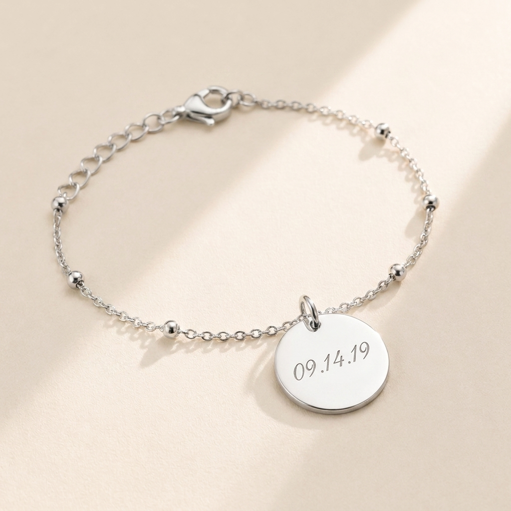 Custom Memorial Bracelet hero photo - sterling silver engraved date disc bracelet on cream background Anthology Jewelry