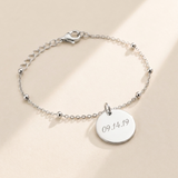 Custom Memorial Bracelet hero photo - sterling silver engraved date disc bracelet on cream background Anthology Jewelry