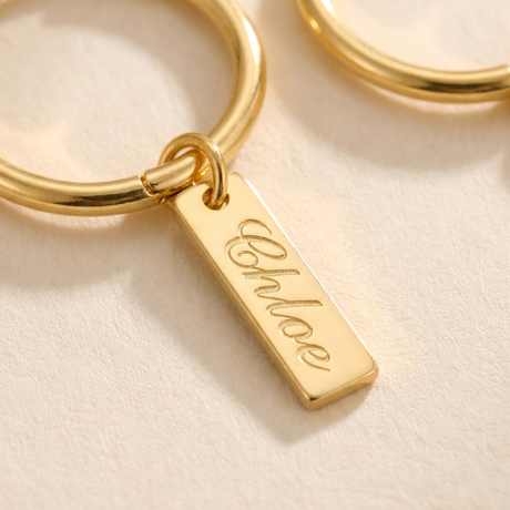 Custom Nameplate Huggie Hoop Earrings detail photo - macro closeup of engraved dangling gold charm and hoop hinge Anthology Jewelry