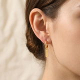 Custom Nameplate Huggie Hoop Earrings lifestyle photo - woman wearing gold huggie hoop earring with engraved charm Anthology Jewelry