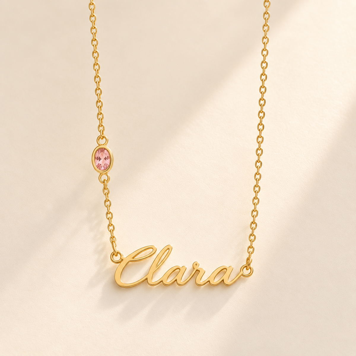 Gold script Clara necklace with one October-pink stone integrated on left chain
