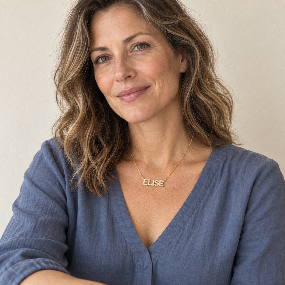 Woman wearing a gold ELISE pavé name necklace in a natural portrait