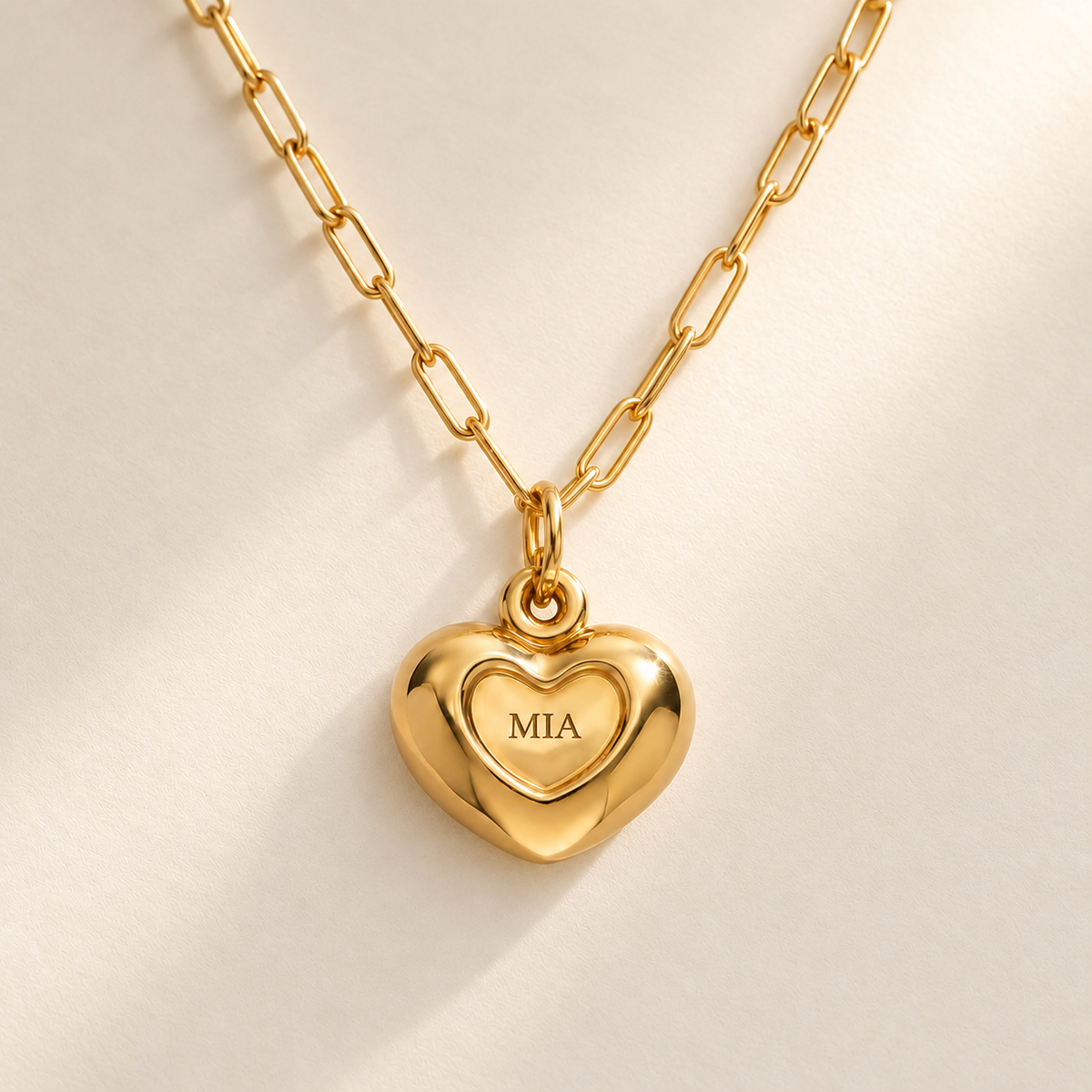 Custom Puffy Heart Necklace hero photo - gold heart with MIA engraving and soft consistent diagonal light Anthology Jewelry