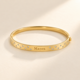 Gold scattered-stone name bangle with Maren engraving, viewed as a horizontal oval