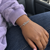 Custom Script Name Bracelet in silver with Clara personalization, worn on a car passenger wrist; illustrative phone-style marketing image - Anthology Jewelry